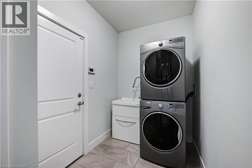 Laundry room featuring stacked washing machine and dryer and light marble finish flooring - 2527 Holbrook Drive, London, ON - Indoor Photo Showing Laundry Room