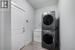 Laundry room featuring stacked washing machine and dryer and light marble finish flooring - 