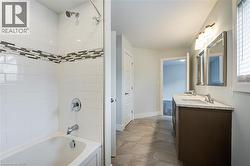Full bath with shower / bathtub combination, double vanity, and dark stone finish flooring - 