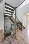 Staircase with wood finished floors, plenty of natural light, and a high ceiling - 