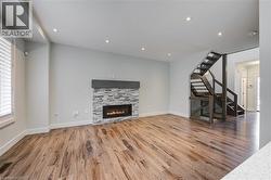Unfurnished living room with stairs, light wood-type flooring, a fireplace, and recessed lighting - 