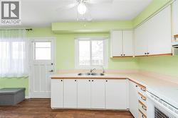 Kitchen with white cabinets, light countertops, and dark wood-style flooring - 