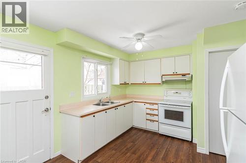 Kitchen featuring white appliances, light countertops, white cabinets, dark wood-style floors, and under cabinet range hood - 48 Riverdale Drive Unit# 2, Hamilton, ON - Indoor Photo Showing Kitchen With Double Sink