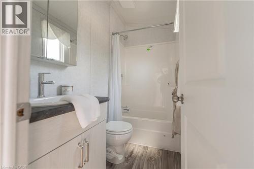 Full bath with vanity, shower / bath combo with shower curtain, and wood finished floors - 85 Hutchinson Beach Road Unit# B56, Huntsville, ON - Indoor Photo Showing Bathroom