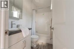 Full bath with vanity, shower / bath combo with shower curtain, and wood finished floors - 