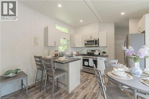 Kitchen with dark countertops, stainless steel appliances, light wood finished floors, a breakfast bar area, and a peninsula - 85 Hutchinson Beach Road Unit# B56, Huntsville, ON - Indoor