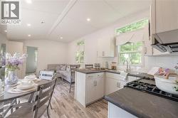 Kitchen with light wood-style floors, vaulted ceiling, backsplash, a peninsula, and white cabinets - 