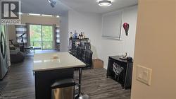 Kitchen with a kitchen island, stainless steel fridge with ice dispenser, a kitchen bar, dark wood-style flooring, and dark cabinets - 