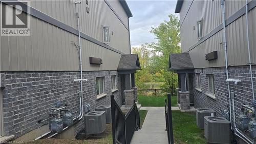 View of side of property with a cooling unit and roof with shingles - 115 South Creek Drive Unit# 15D, Kitchener, ON - Outdoor With Exterior