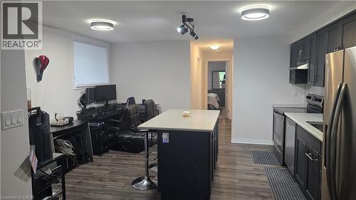 Kitchen with dark cabinetry, stainless steel appliances, an office area, a center island, and dark wood-style flooring - 115 South Creek Drive Unit# 15D, Kitchener, ON - Indoor Photo Showing Kitchen