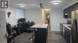 Kitchen with dark cabinetry, stainless steel appliances, an office area, a center island, and dark wood-style flooring - 