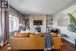 Family Room with a stone fireplace and huge window overlooking deck and greenspace beyond - 