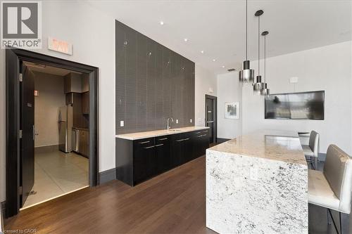 Kitchen in party room featuring a kitchen breakfast bar, dark cabinets, light stone countertops, pendant lighting, and stainless steel appliances - 55 Speers Road Unit# 415, Oakville, ON - Indoor Photo Showing Kitchen With Upgraded Kitchen