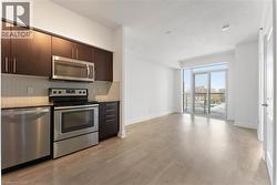Kitchen featuring appliances with stainless steel finishes, dark brown cabinetry, light wood-style floors, backsplash, and a textured ceiling - 