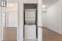 Laundry room with light wood finished floors and estacked washer and dryer - 