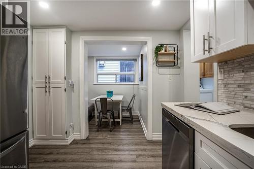 Kitchen with freestanding refrigerator, light stone counters, dishwasher, white cabinetry, and recessed lighting - 21 Chatham Street, Hamilton, ON - Indoor