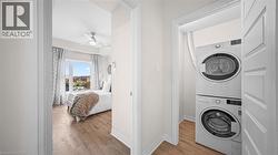 Washroom with light wood finished floors, stacked washer / dryer, and ceiling fan - 