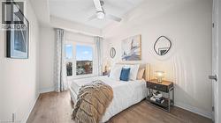 Bedroom with wood finished floors, ceiling fan, and a tray ceiling - 