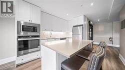 Kitchen with decorative backsplash, a kitchen bar, appliances with stainless steel finishes, white cabinets, and light stone counters - 