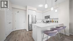 Kitchen featuring appliances with stainless steel finishes, a breakfast bar area, light wood-style flooring, and white cabinets - 