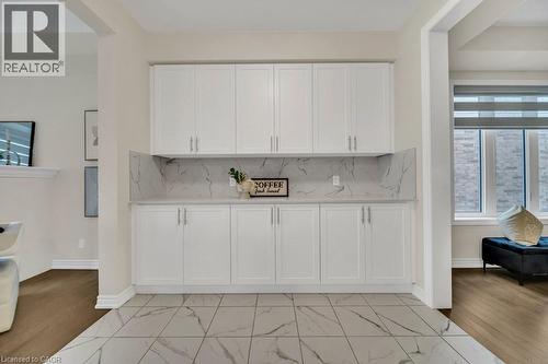 Kitchen with white cabinetry, decorative backsplash, light stone countertops, and light wood-style flooring - 285 Broadacre Drive, Kitchener, ON - Indoor