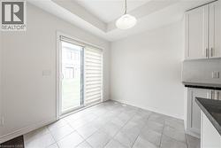 Unfurnished dining area featuring a raised ceiling and light tile patterned floors - 