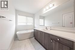 Full bath with vanity, a soaking tub, and light tile patterned floors - 