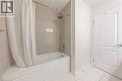 Bathroom featuring shower / bath combo and light tile patterned floors - 