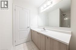 Bathroom featuring vanity, a tile shower, and light tile patterned floors - 
