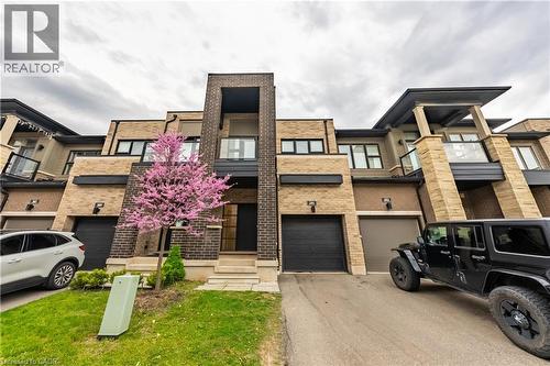 View of front facade with brick siding, driveway, and a balcony - 391 Athabasca Common, Oakville, ON - Outdoor With Facade