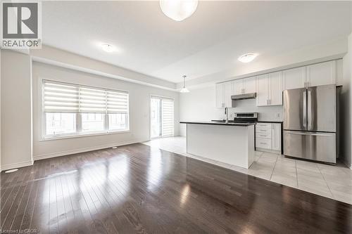 Kitchen with stainless steel appliances, white cabinets, dark countertops, open floor plan, and hanging light fixtures - 391 Athabasca Common, Oakville, ON - Indoor Photo Showing Kitchen