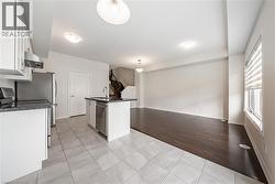 Kitchen featuring white cabinets, light tile patterned flooring, stainless steel appliances, open floor plan, and wall chimney exhaust hood - 