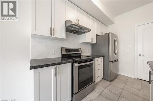 Kitchen featuring appliances with stainless steel finishes, white cabinetry, under cabinet range hood, and tasteful backsplash - 391 Athabasca Common, Oakville, ON - Indoor Photo Showing Kitchen