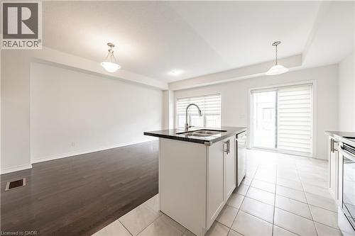 Kitchen with white cabinets, a kitchen island with sink, hanging light fixtures, appliances with stainless steel finishes, and light tile patterned floors - 391 Athabasca Common, Oakville, ON - Indoor Photo Showing Kitchen
