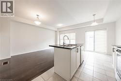 Kitchen with white cabinets, a kitchen island with sink, hanging light fixtures, appliances with stainless steel finishes, and light tile patterned floors - 