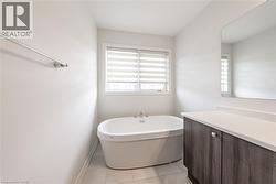 Full bath with a freestanding tub, vanity, and light tile patterned floors - 