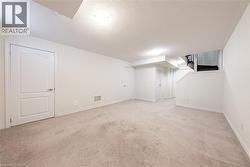 Finished basement featuring a textured ceiling, light carpet, and stairs - 