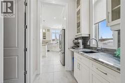 Kitchen featuring glass insert cabinets, white cabinetry, light stone countertops, recessed lighting, and high end refrigerator - 