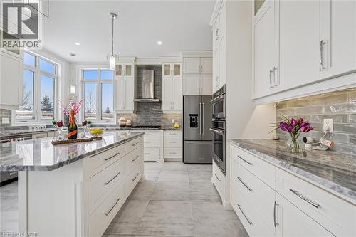 Kitchen with glass insert cabinets, appliances with stainless steel finishes, wall chimney range hood, light stone counters, and hanging light fixtures - 263 Chestnut Ridge, Waterloo, ON - Indoor Photo Showing Kitchen With Upgraded Kitchen