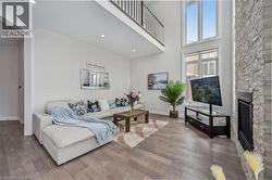 Living area featuring a stone fireplace, a towering ceiling, and wood-type flooring - 