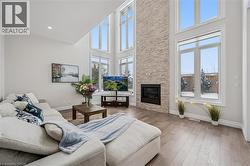 Living room featuring wood finished floors, a high ceiling, and a stone fireplace - 