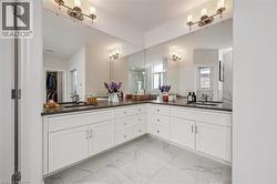 Bathroom featuring double vanity, light marble finish flooring, and a walk in closet - 