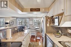 Kitchen featuring white cabinets, a chandelier, stainless steel dishwasher, and light stone counters - 