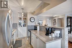 Kitchen with white cabinetry, stainless steel appliances, pendant lighting, light stone countertops, and open floor plan - 