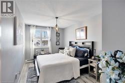 Bedroom featuring light wood finished floors, a textured ceiling, and a baseboard radiator - 