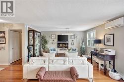 Living room featuring a wall mounted AC, light wood-style flooring, and a textured ceiling - 
