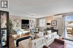 Living room with wood finished floors, a wall unit AC, a textured ceiling, and a chandelier - 