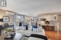 Living room featuring wood finished floors, a wall mounted air conditioner, a textured ceiling, and a chandelier - 