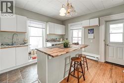 Kitchen featuring white cabinets, a kitchen bar, decorative light fixtures, a chandelier, and a kitchen island - 