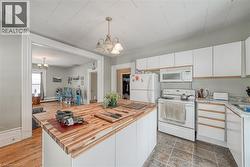 Kitchen featuring white cabinets, white appliances, a chandelier, and hanging light fixtures - 